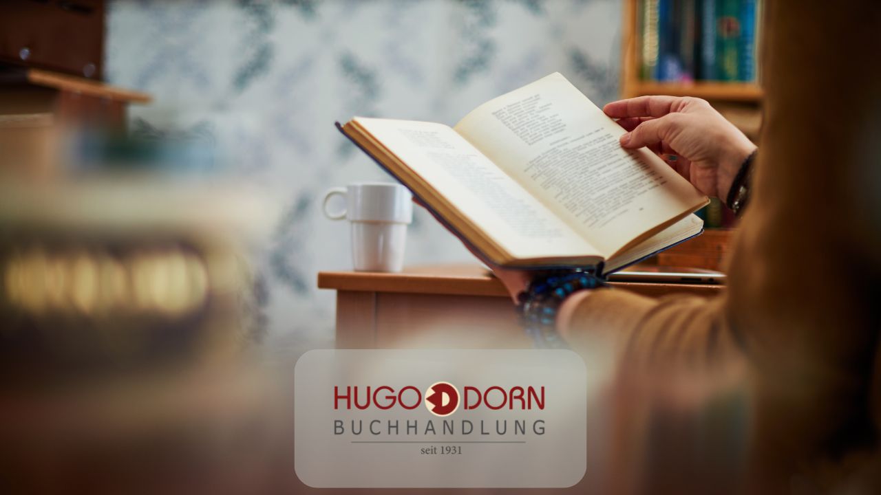 jemand hält und liest ein aufgeschlagenes Buch mit einer Tasse Kaffee